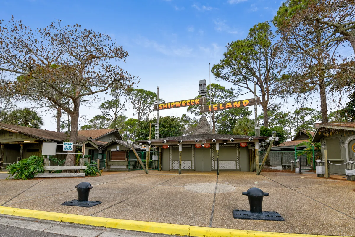 The welcoming entrance of Shipwreck Island Water Park, with its bold signage and lush landscaping, sets the stage for exciting off-site family adventures. The entrance is vibrant and inviting, surrounded by trees and nautical-themed decor.