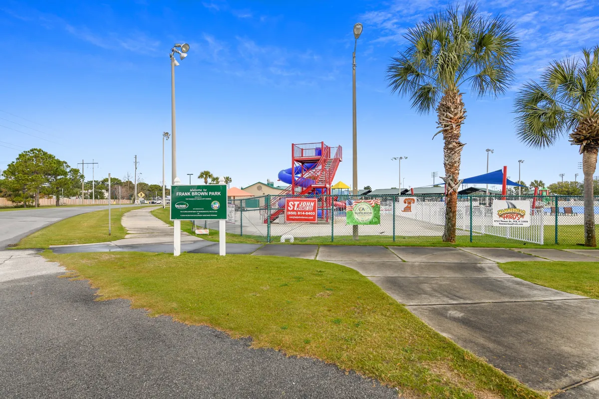 An inviting exterior scene featuring a water slide surrounded by palm trees and clear park signage, capturing a joyful family-friendly environment ideal for summer fun and relaxation.