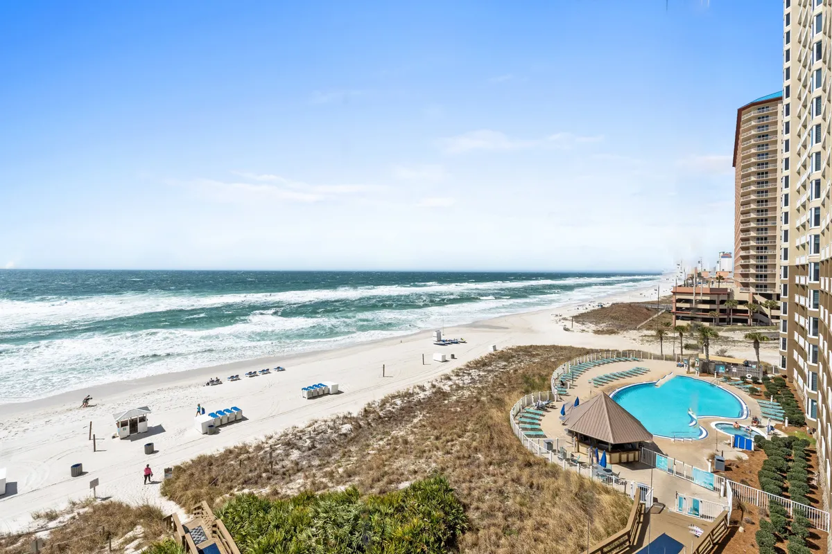 A tranquil view of the resort's pool area with beach chairs, the ocean in the background, and the hotel building visible, capturing both relaxation and easy access to amenities.