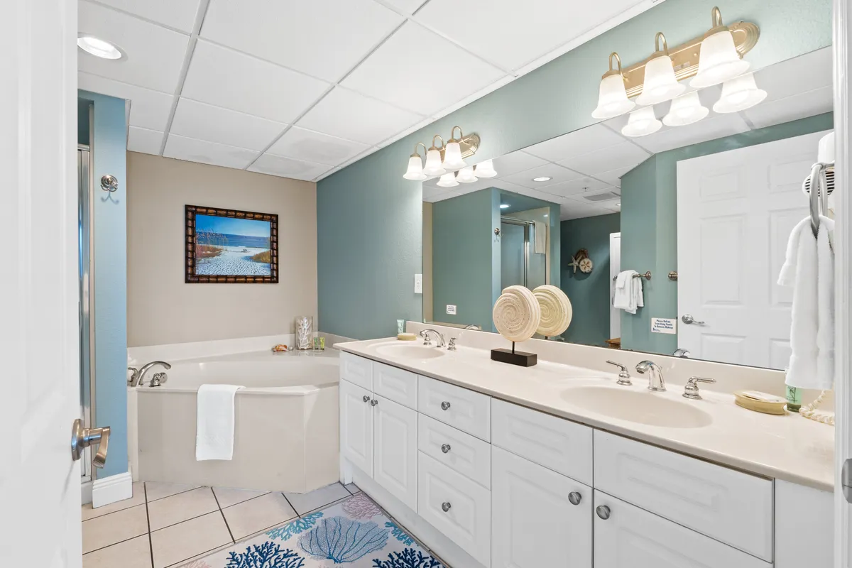 A serene and well-lit bathroom with a double vanity, large mirror, stylish lighting, and a spacious bathtub. The space feels both luxurious and practical, ideal for unwinding or getting ready for the day.